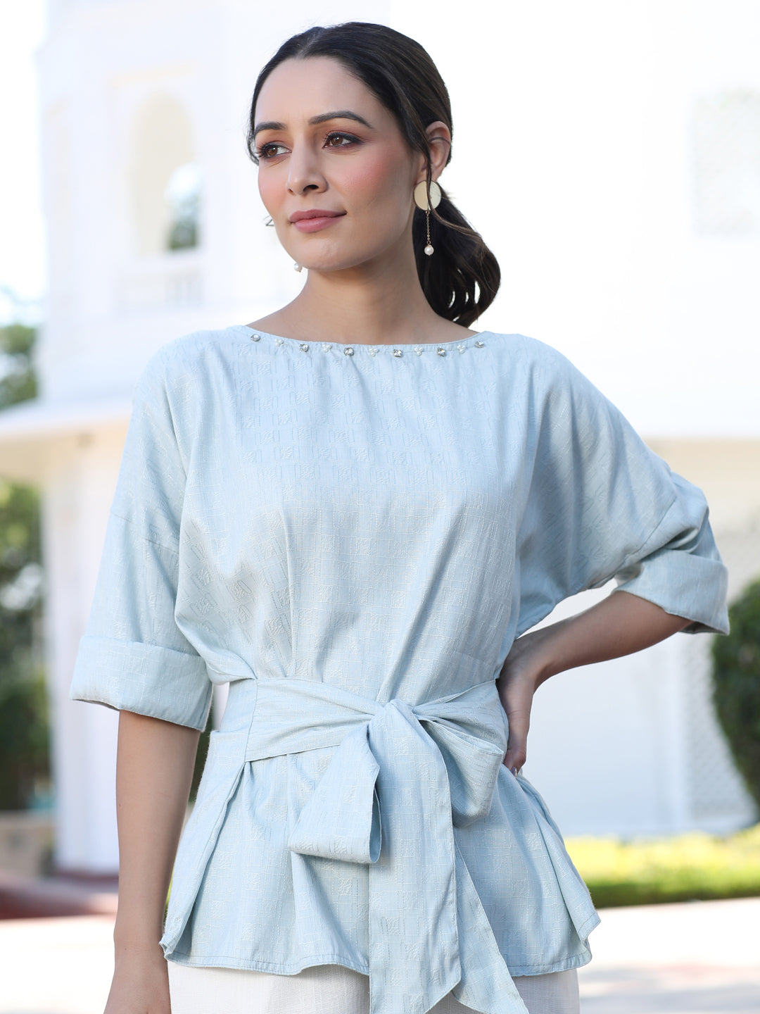 A Light Blue Color Self Weaved Embellished Top With Tie-Up At The Waist And Extended Sleeves Top With Cotton White Flared Pants