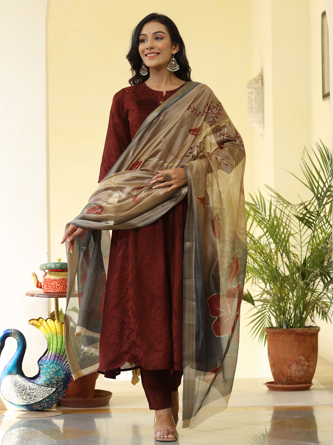 Brown Silk Pleated Straight Kurta Has Round Neck, Front Placket And Buttons With Both Side Pleats, Three Fourth Regular Sleeves, Flared Hemline, Cotton Mulmul Lining Is Attached To Kurta, Brown Pants Has Both Side Pocket And Partially Elastic Waist, Organza Printed Dupatta.