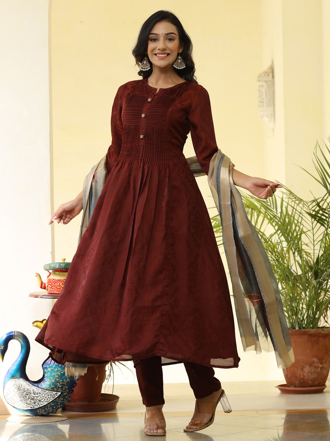 Brown Silk Pleated Straight Kurta Has Round Neck, Front Placket And Buttons With Both Side Pleats, Three Fourth Regular Sleeves, Flared Hemline, Cotton Mulmul Lining Is Attached To Kurta, Brown Pants Has Both Side Pocket And Partially Elastic Waist, Organza Printed Dupatta.